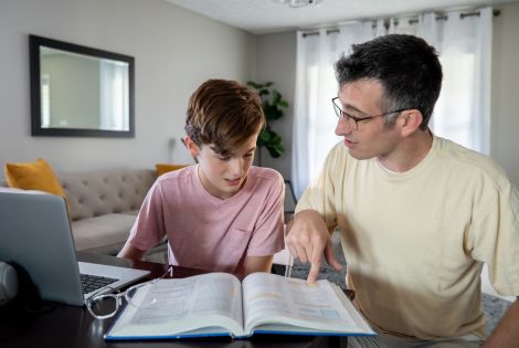 Photo of a son and father looking at a textbook to illustrate the article 