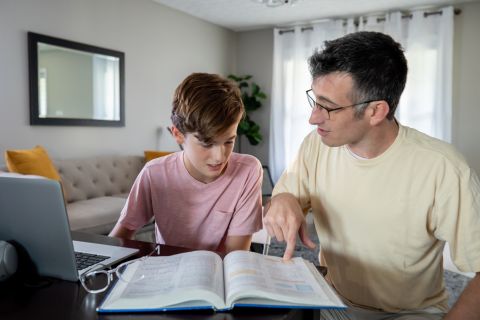 Photo of a son and father looking at a textbook to illustrate the article 