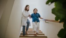 Photo of a younger person helping an older person down the stairs, to illustrate the article 