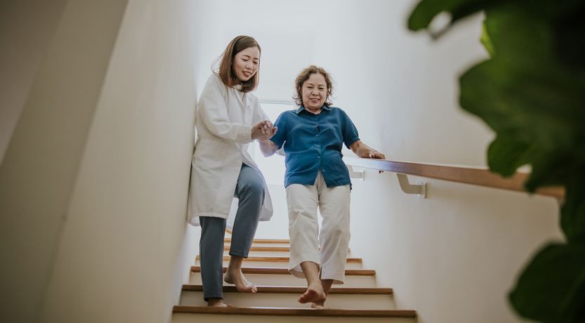 Photo of a younger person helping an older person down the stairs, to illustrate the article 
