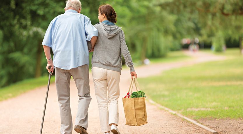 A photo of an older man with a cane walking with a younger woman to illustrate the article A Biblical Perspective on Caregiving