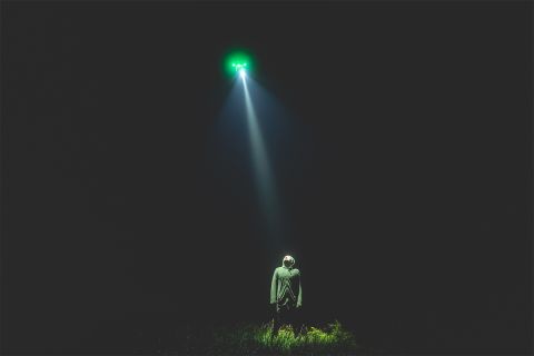 Photo illustration of a light shining down from the sky on a person to accompany the article Are Aliens Real?