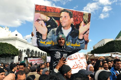 <p>Tunisian protesters demonstrate beneath a poster of Mohamed Bouazizi.</p>