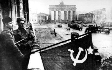 The Brandenburg Gate stands in the background as Soviet soldiers wave their flag after the Battle of Berlin in May of 1945.
