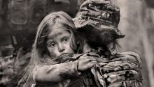 Photo of dazed young girl being carried by a soldier in a war setting to illustrate the article Why War?