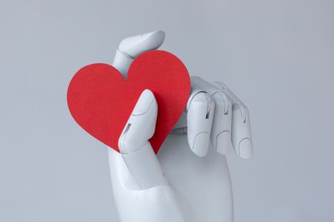 Graphic of a robot hand holding a red heart to illustrate the article 