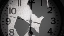 A man's shadow over a clockface to illustrate the article 