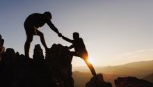 Photo of a mountain climber helping another mountain climber to illustrate the article 
