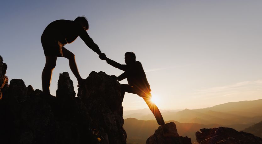 Photo of a mountain climber helping another mountain climber to illustrate the article 