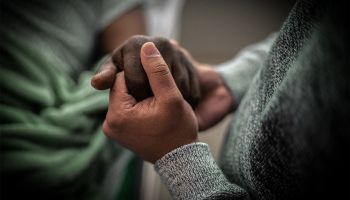 Two people clasping hands in grief and comfort to illustrate the article The Art of Dying Well