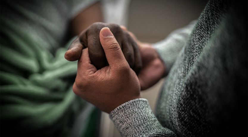Two people clasping hands in grief and comfort to illustrate the article The Art of Dying Well