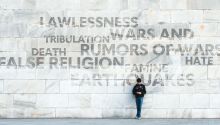 Person standing in front of a large wall displaying negative words associated with the end times, to illustrate the article 