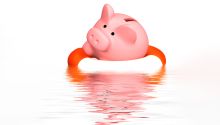 Illustration of a piggy bank in a life saver ring on the water, to represent the article How to Deal With Financial Problems