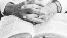 Older person's hands folded on a Bible to illustrate the Legacy of Older Christians
