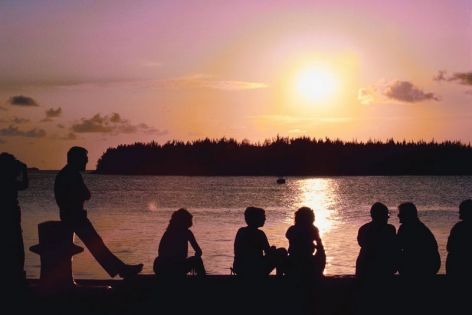 Relationships: group talking at a lake at sunset.