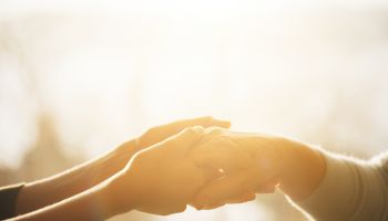 Photo of hands holding another's hand to illustrate the article 