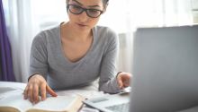 Photo of a woman reading a Bible in front of a computer to illustrate the article The Best Bible Study Tools Online