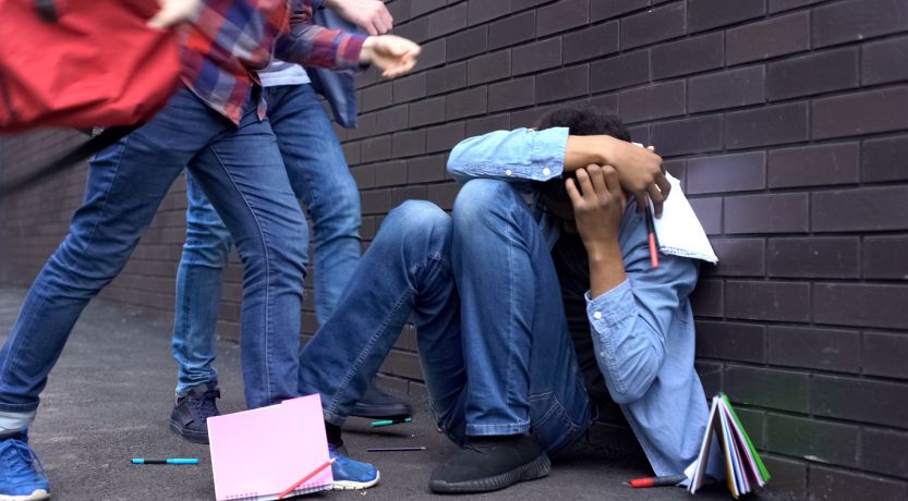 What Causes Violence? Illustrated by a photo of a student being attacked by other students.