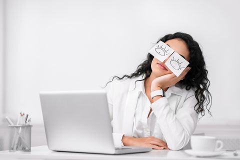 What Does the Bible Say About Quiet Quitting? Photo illustration of woman at work with paper open eyes taped over her eyes.