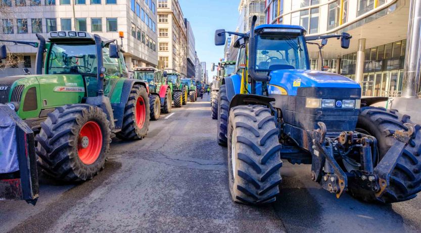 Photo of tractors on a city street as part of a protest, to illustrate the article, Why Farmers Are Protesting Around the World