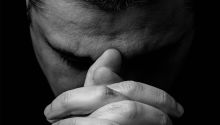 Photo of a man's face with his hands clasped in front of him in prayer, to illustrate the article Why Pray?