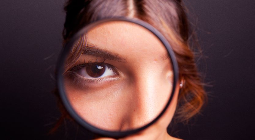Photo of a girl looking through a magnifying glass at the camera, to illustrate the article Why We Need Spiritual Discernment Now More Than Ever