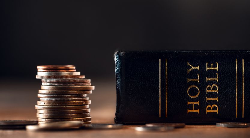 Photo of a stack of coins next to a Bible, to illustrate the article You Cannot Serve God and Money