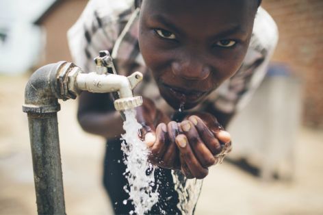 <p>A farm employee in northern Uganda drinks from a well.</p>