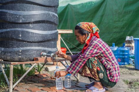 <p>A Nepalese earthquake survivor obtains water from a tank at a relief camp after already scarce water sources were contaminated by the disaster.</p>