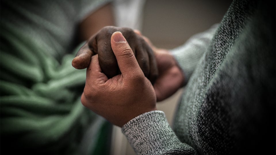 Two people clasping hands in grief and comfort to illustrate the article The Art of Dying Well
