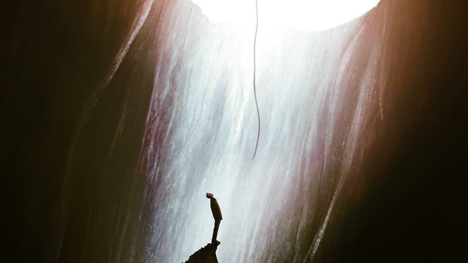 Illustration of a person looking up from inside a huge hole toward a rope and the far away light, to illustrate the article 