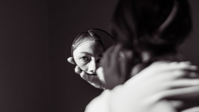 Dark photo of a girl's face reflected in a small round mirror to illustrate the article 