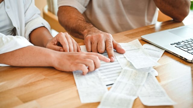 Photo of a man and woman's hands pointing to receipts and other financial documents to illustrate the article Money and Marriage: 7 Cs for Reducing Financial Friction
