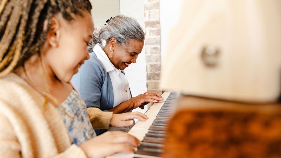 A photo of perhaps a granddaughter and grandmother playing piano together to illustrate the article How Can We “Rejoice Always”?